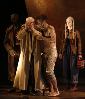 Lear with hands holding up to his head and long robe, mud-streaked Poor Tom weareing only pants holding Lear up, and Fool with a squeze box and long winter's cap on his head in background